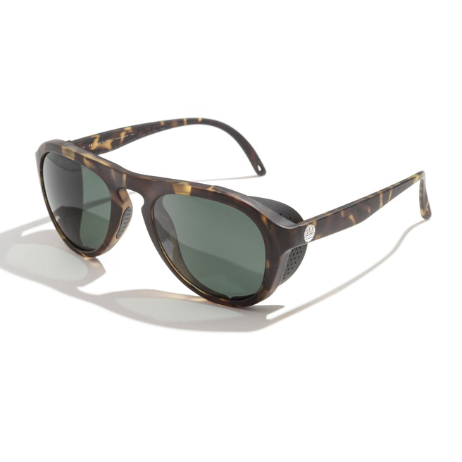 Sunglasses with tortoiseshell frame and green lenses on a white background