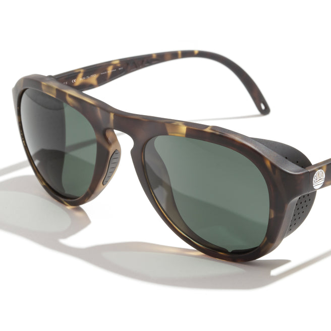 Sunglasses with tortoiseshell frame and green lenses on a white background