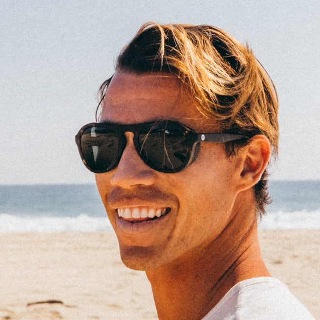 Man wearing sunglasses on a beach with ocean in the background