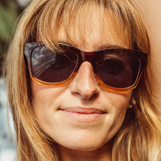 Close-up of a person wearing sunglasses with a blurred background