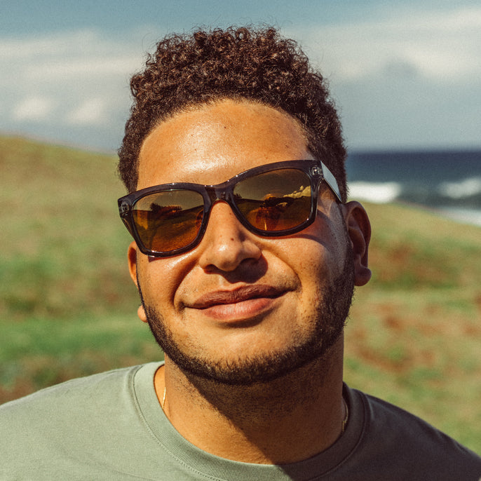 man wearing stylish black sunglasses in front of a green field