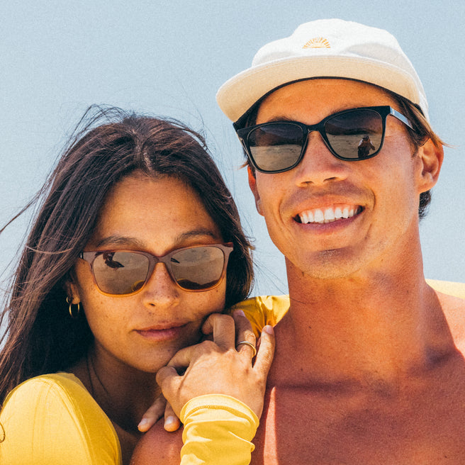 Two people wearing sunglasses with a clear blue sky background
