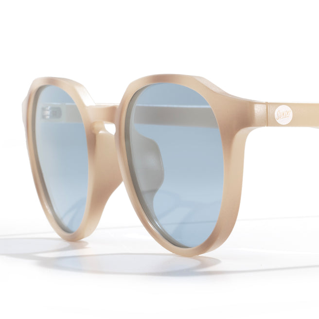 Beige sunglasses with blue lenses on a white background