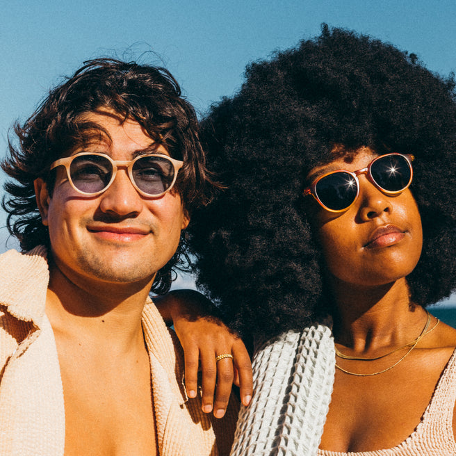 Two people wearing sunglasses with a clear blue sky background