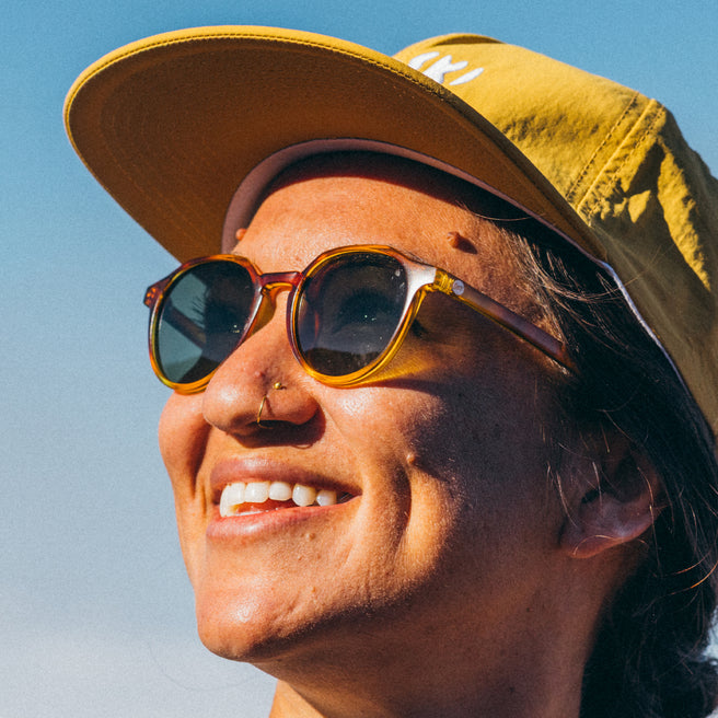 Person wearing a yellow cap and sunglasses against a clear blue sky