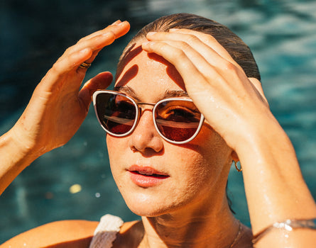 girl pushing hair out of her face in pool wearing sunski catalina sunglasses