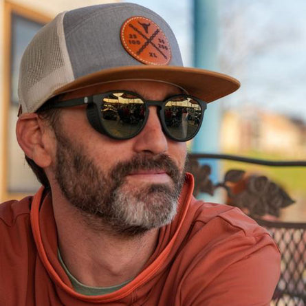 Man wearing a cap and sunglasses with a blurred background