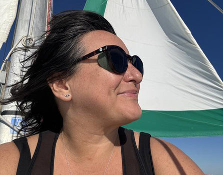 Woman wearing sunglasses with a sailboat in the background