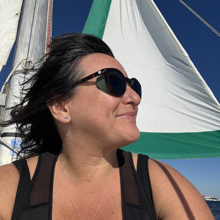 Woman wearing sunglasses with a sailboat in the background
