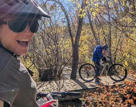 Two people with bicycles in a forest setting with autumn leaves