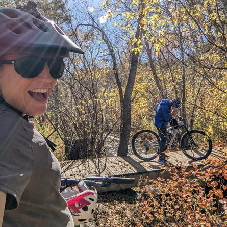 Two people with bicycles in a forest setting with autumn leaves