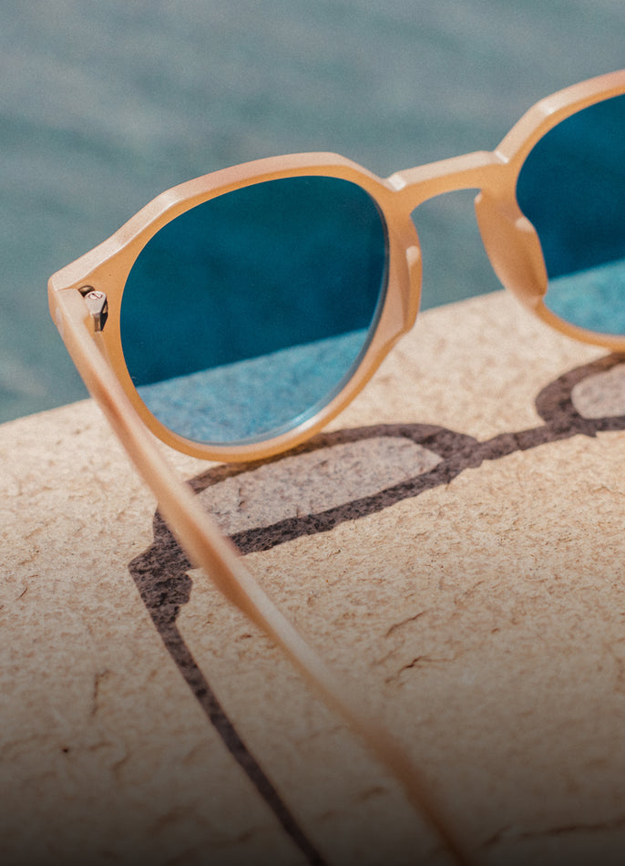 Sunglasses with blue lenses on a rock by the water