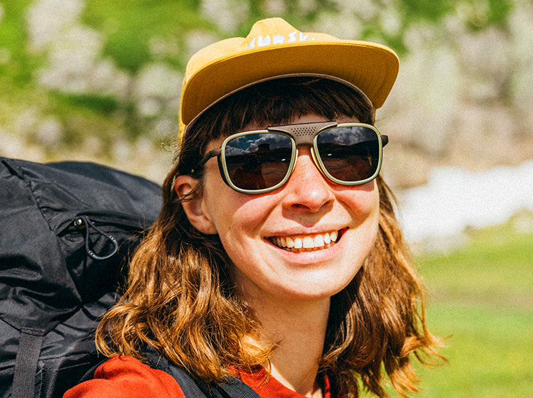 Person wearing a yellow cap and sunglasses with a blurred natural background