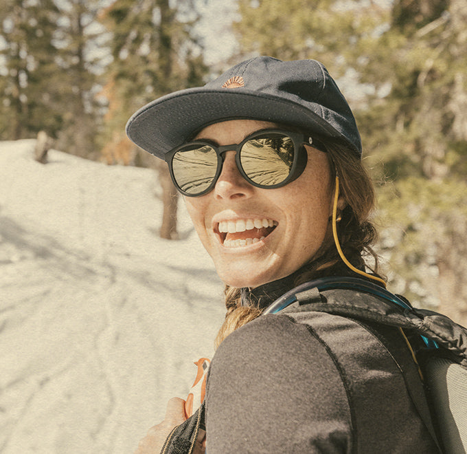 girl smiling in the snow wearing sunski hat