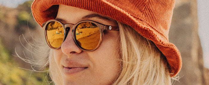 girl wearing a hat looking over shoulder wearing sunski dipsea sunglasses