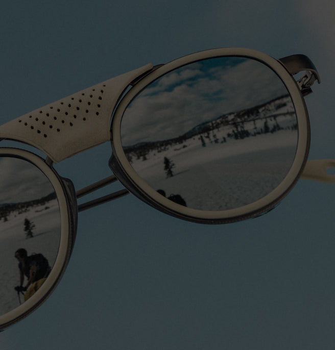 Wooden sunglasses with reflective lenses showing a snowy landscape and person with a dog.