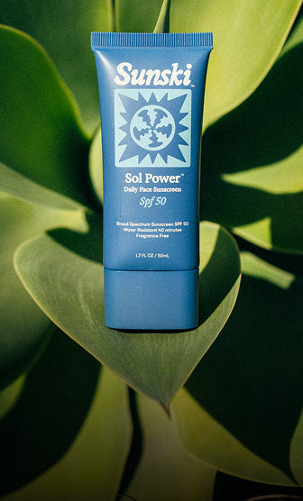 Blue Sunsiki sunscreen tube on green leaves