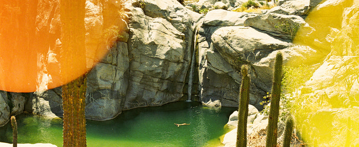 Rocky landscape with a pool of water and orange and yellow fabric.