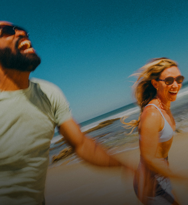 Two people walking on a beach with clear blue sky