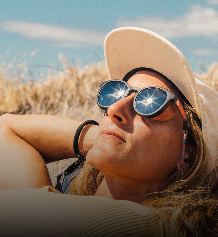Person wearing sunglasses and a hat in a sunlit outdoor setting
