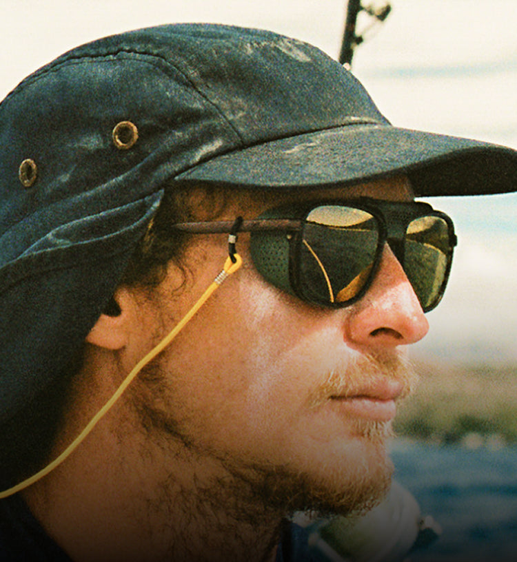 Person wearing a green cap and sunglasses with a blurred natural background
