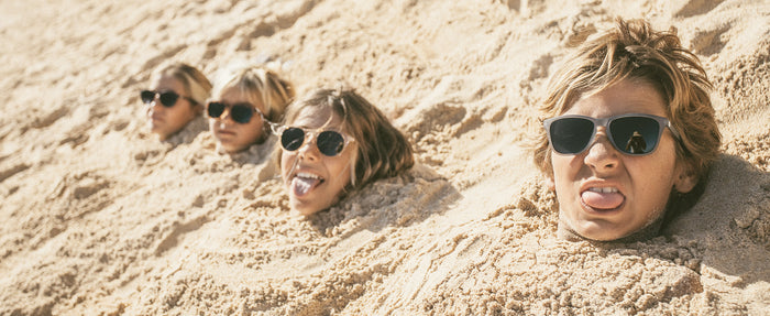 kids buried in sand wearing sunski kids' polarized sunglasses