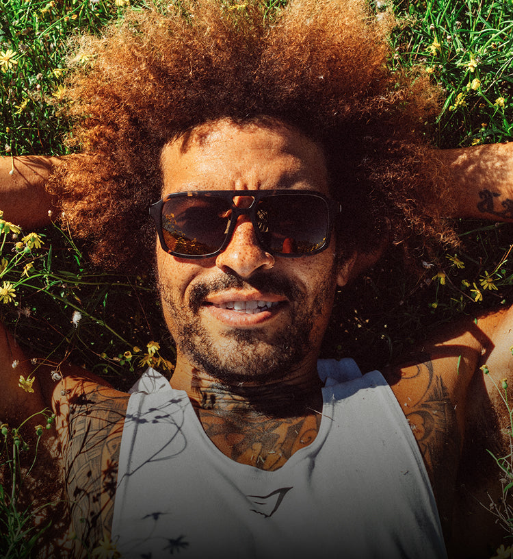 Man with sunglasses and tattoos lying on grass with flowers
