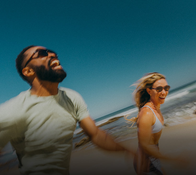 Two people walking on a beach with clear blue skies