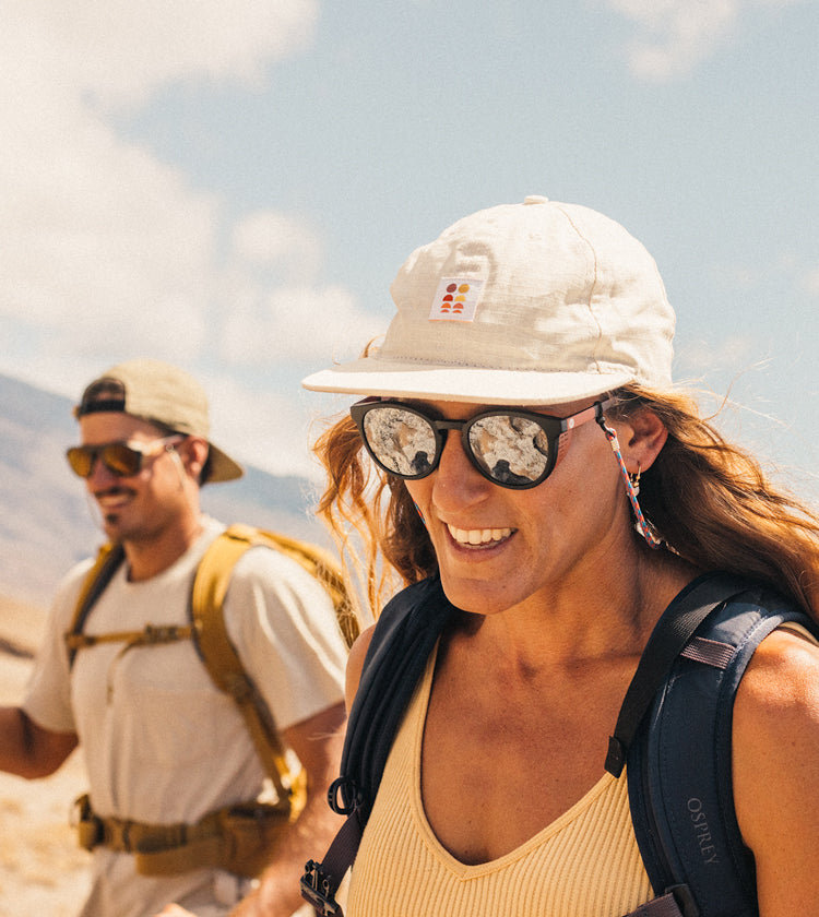 Two people hiking with backpacks and sunglasses in a desert setting