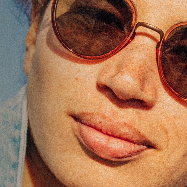 Close-up of a person wearing round sunglasses with a blurred background