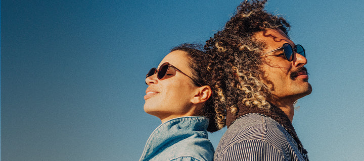 Two people wearing sunglasses against a clear blue sky