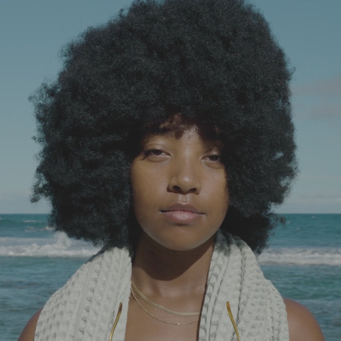 a video of a woman with an afro trying on sunglasses