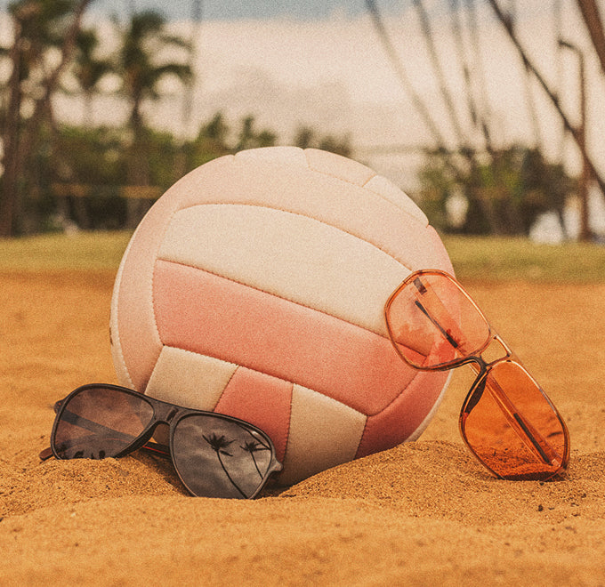 sunski sunglasses resting on a volleyball at the beach