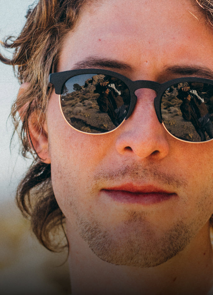 Close-up of a person wearing reflective sunglasses with a blurred background
