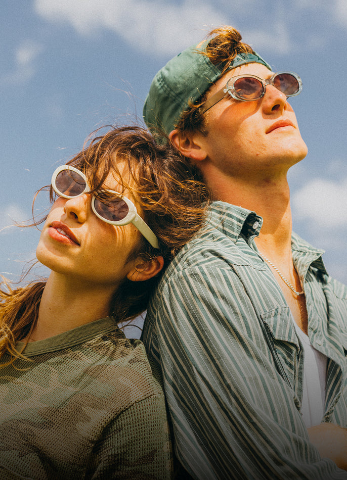 Two people wearing sunglasses and a headband against a blue sky.