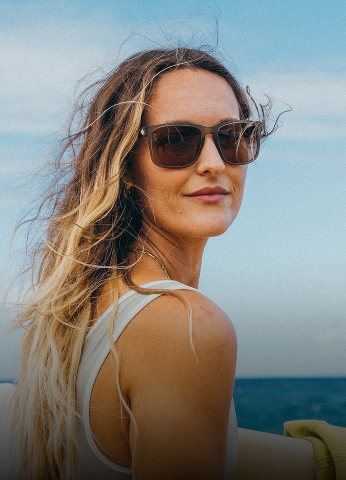 Woman wearing sunglasses with a blurred ocean and sky background