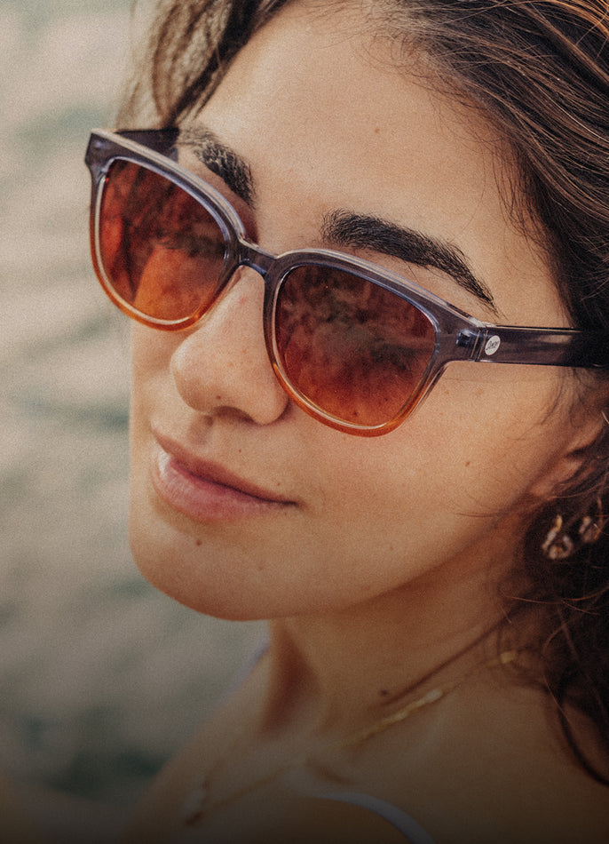 Close-up of a person wearing sunglasses with a blurred natural background