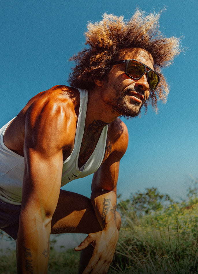 Man with sunglasses and a white tank top outdoors on a clear day
