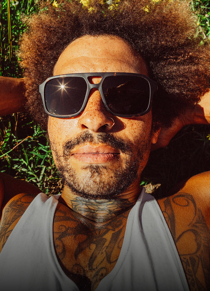 Man with sunglasses and tattoos in a natural setting