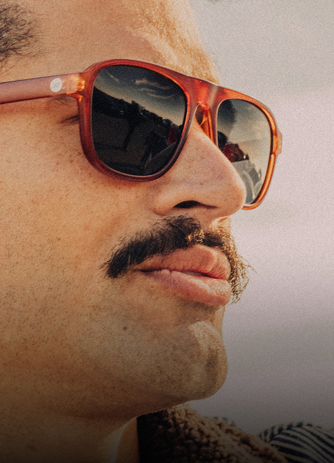 Close-up of a person wearing orange sunglasses with a blurred background