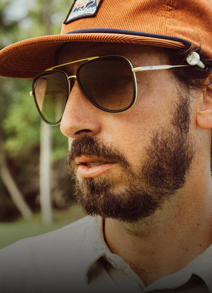 Man wearing sunglasses and an orange cap with a blurred natural background