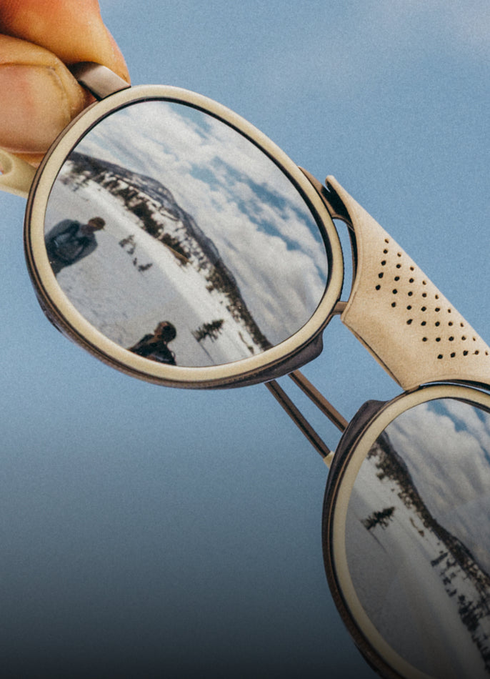 Sunglasses with mountain reflection against a blue sky