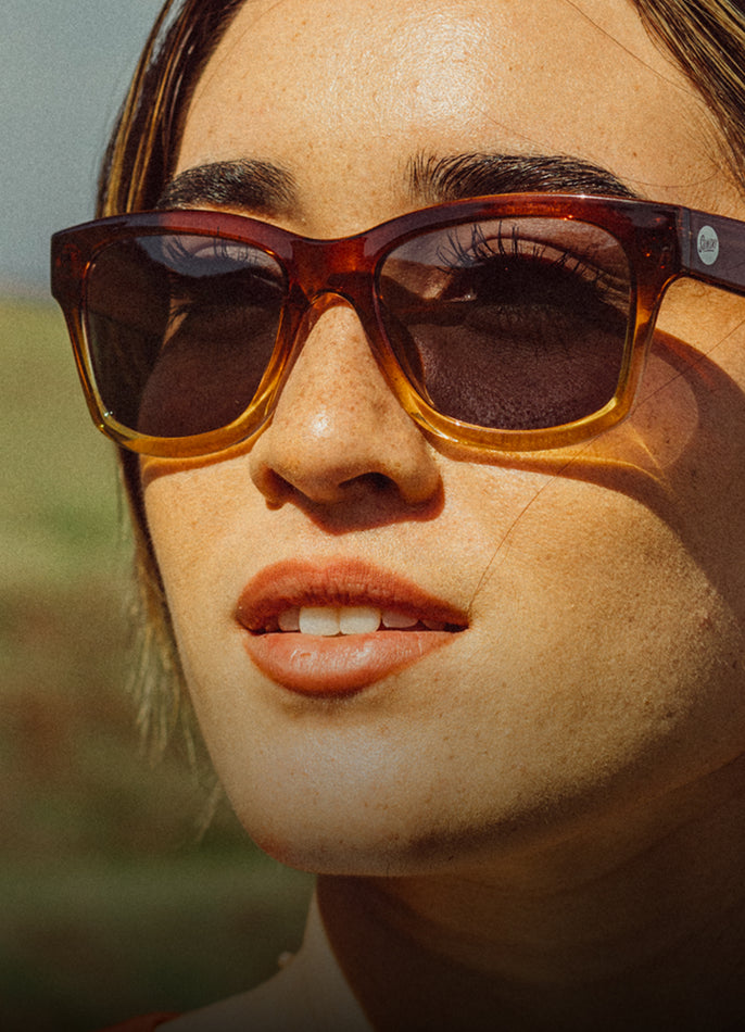 Close-up of a person wearing sunglasses with a blurred natural background