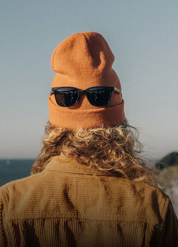 Person wearing an orange beanie and sunglasses with a blurred background
