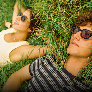 Two people lying on grass wearing sunglasses