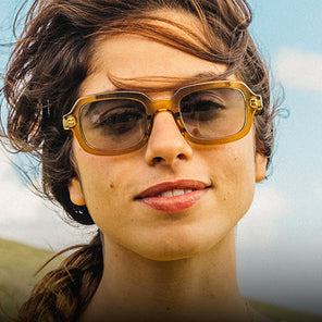 Close-up of a person wearing sunglasses with a blurred natural background