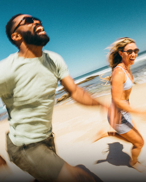 Two people running on a beach with clear blue sky