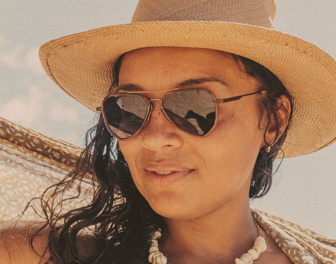 woman in a straw hat wearing sunski astra sunglasses