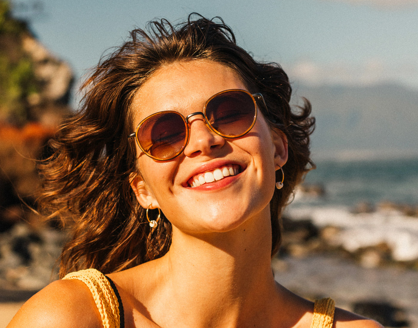 woman laughing with wind blowing wearing sunski baia sunglasses