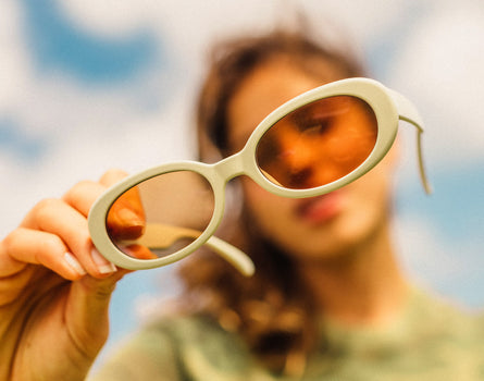 girl holding sunski bianca sunglasses up to camera